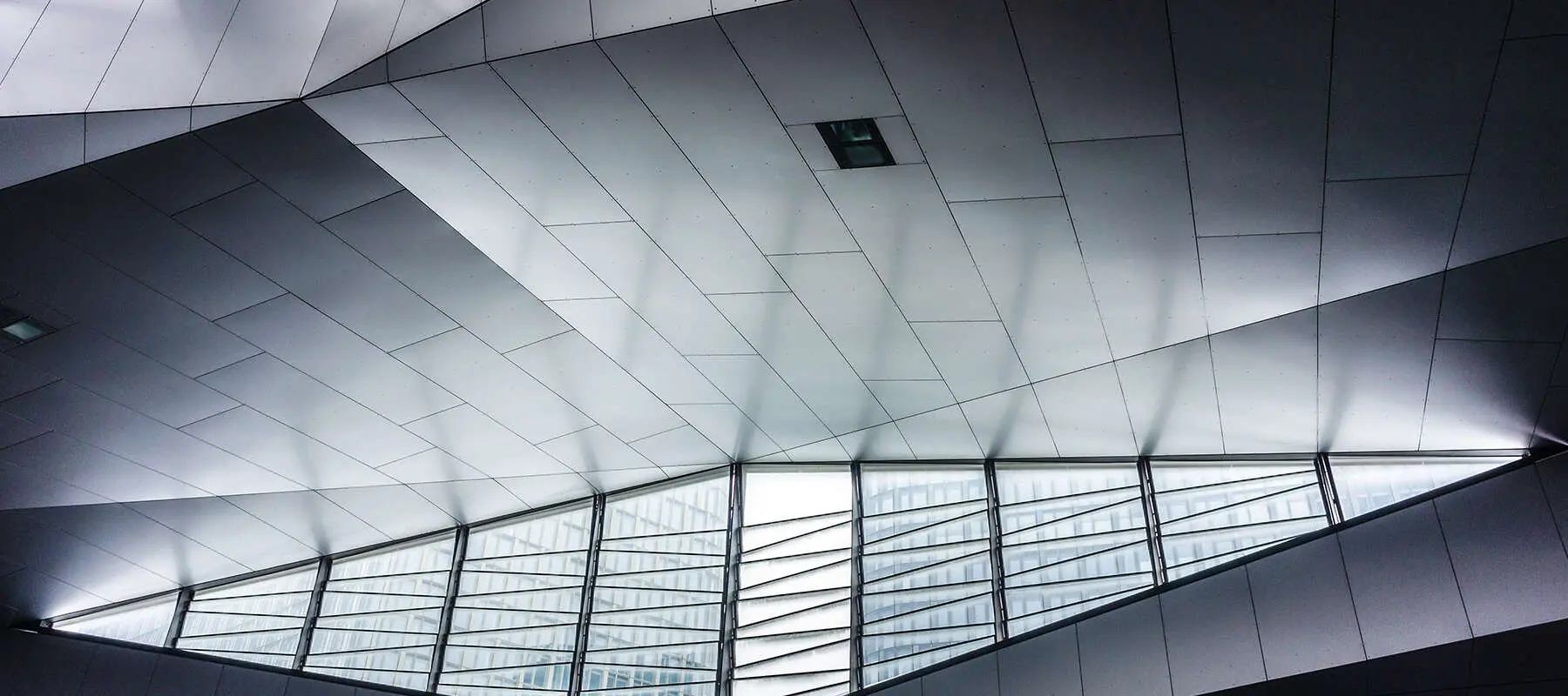 Modern architectural ceiling with geometric patterns and large windows.